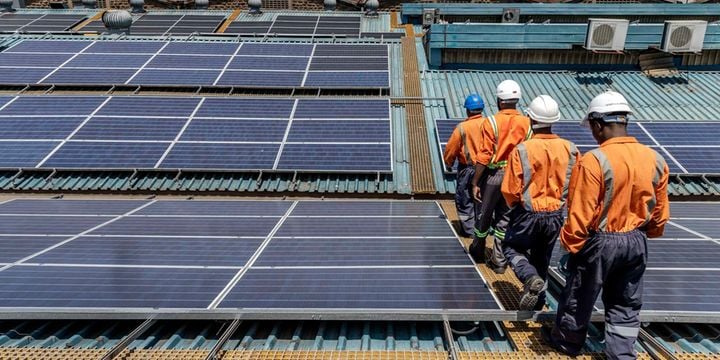 La energía renovable provocará un auge de empleos en África para 2030 GPT Trabajadores con cascos y uniformes de seguridad inspeccionan una instalación de paneles solares sobre un techo industrial.