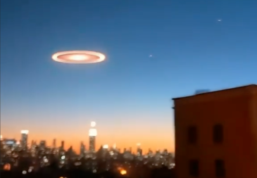 Drones New Jersey Una imagen que muestra un horizonte urbano al atardecer, con un cielo azul degradado hacia tonos anaranjados. En el centro del cielo, se ve un objeto circular brillante con un anillo luminoso, que parece suspendido sobre la ciudad. El paisaje incluye edificios y luces que destacan en la oscuridad creciente, con un rascacielos iluminado en el centro de la escena.