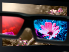 Gafas de cristal líquido bloquean la luz que desencadena crisis epilépticas Unas gafas especiales en primer plano que muestran una vista dividida: el lado izquierdo de las lentes tiene un filtro rojo, mientras que el lado derecho muestra colores vibrantes y nítidos, como una flor rosa y azul. En el fondo, se observa una pantalla con flores que destacan por sus colores menos saturados fuera de las lentes.