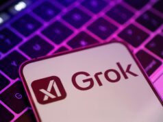 Elon Musk lanza Grok-3 para competir con ChatGPT y DeepSeek Teléfono móvil con el logo de Grok, el chatbot de inteligencia artificial de xAI, sobre un teclado iluminado con luces en tonos morados y rosados.