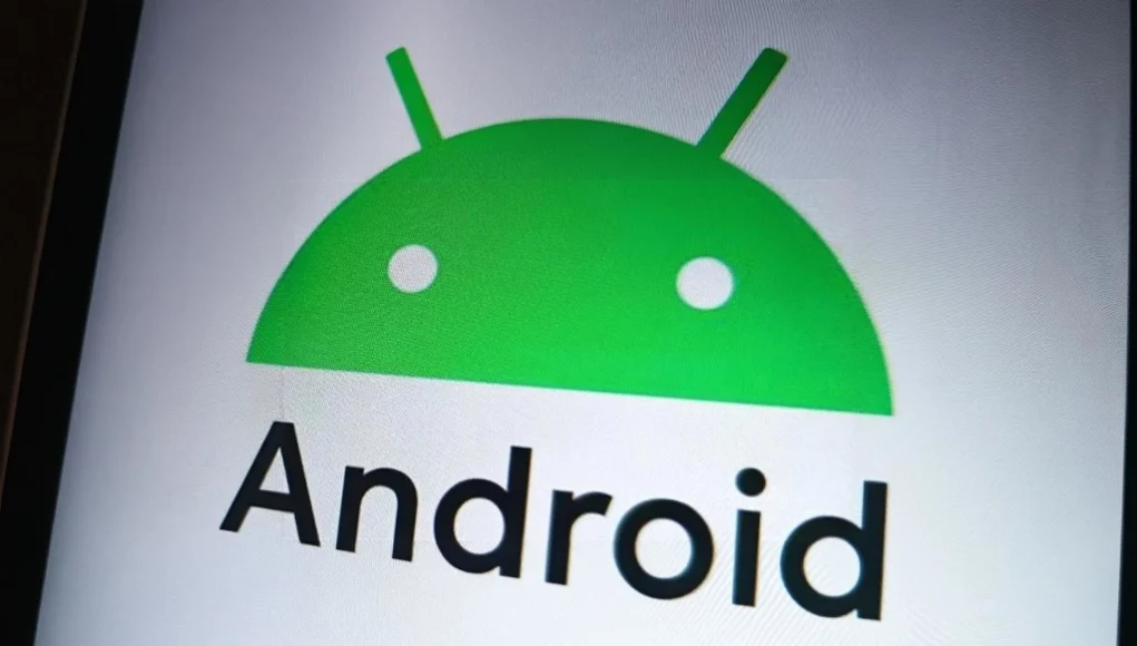Primer plano del logotipo de Android en pantalla, con el característico icono verde del robot en forma de cabeza semicircular con dos antenas, acompañado del texto "Android" en letras negras sobre fondo blanco.