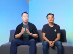 Cognition adquiere Windsurf tras la controversia con Google y OpenAI Dos hombres sentados en un sofá frente a un fondo degradado azul claro. El hombre a la izquierda gesticula mientras habla y lleva un reloj azul, camiseta verde y chaqueta negra. El hombre a la derecha, con gafas y camiseta negra con un logotipo blanco, permanece tranquilo con las manos entrelazadas.