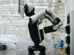 Walker S2: El robot humanoide que cambia sus propias baterías Robot humanoide de color blanco y negro realizando tareas frente a una máquina en una moderna fábrica automatizada, rodeado de estructuras industriales iluminadas con luz blanca.