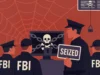 Desmantelado el imperio de ransomware BlackSuit en una operación internacional Ilustración digital en estilo plano que muestra a varios agentes del FBI y un oficial de policía frente a pantallas de ordenador con un icono de calavera y huesos cruzados encadenado con un candado, simbolizando la incautación de sistemas relacionados con cibercrimen. Uno de los agentes sostiene un cartel con la palabra “SEIZED” (incautado). El fondo es rojo con un gran diseño de telaraña y pequeños candados, representando la red criminal desmantelada.