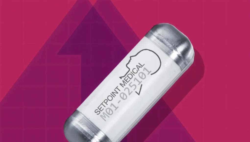 Dispositivo médico en forma de cápsula sobre fondo rosa, con la inscripción “SETPOINT MEDICAL” y el contorno de una cabeza humana impreso en su superficie.