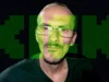 Kick enfrenta multa de $49 millones tras la muerte en directo del streamer francés Jean Pormanove Retrato de un hombre con gafas y camiseta oscura sobre un fondo negro, con el logotipo de la plataforma de streaming “Kick” superpuesto en grande y color verde neón, parcialmente transparente sobre su rostro.