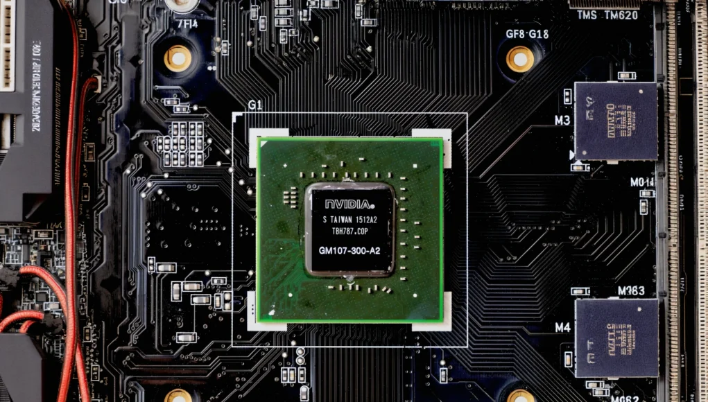 Una placa base con un chip gráfico NVIDIA instalado en el centro, rodeado de circuitos electrónicos y componentes.