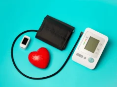 Un nuevo fármaco derrota la hipertensión más rebelde por primera vez en décadas Equipo médico sobre fondo azul: un tensiómetro digital con brazalete negro, un oxímetro de pulso blanco y un corazón rojo decorativo, simbolizando el monitoreo de la salud cardiovascular.