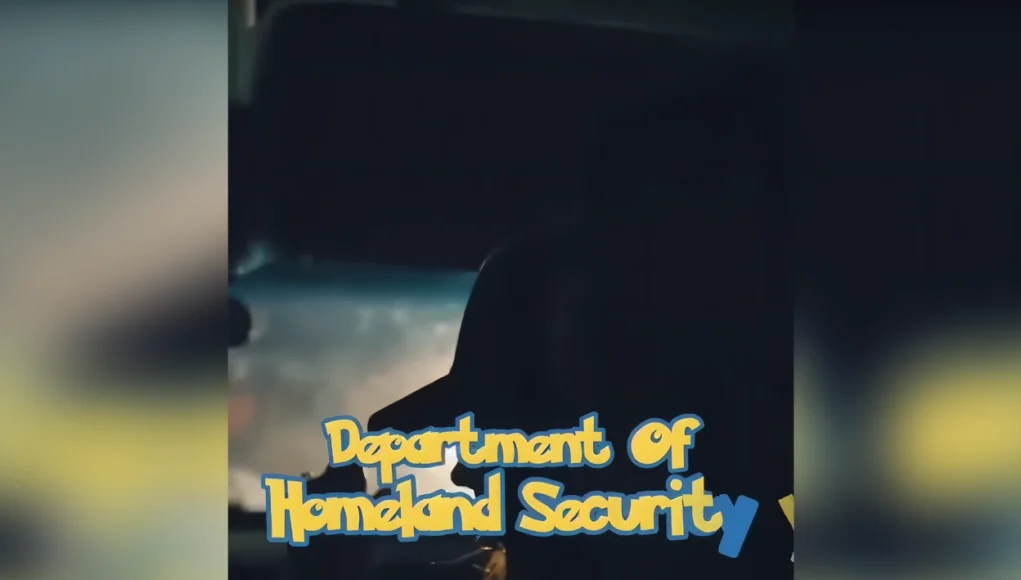 Captura de un video oscuro con la silueta de una persona dentro de un vehículo. En el centro aparece superpuesto el texto ‘Department of Homeland Security’ con un estilo de tipografía colorida que imita un diseño infantil o de caricatura.