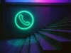 Neon Mobile, la aplicación número 2 en App Store que paga por grabar llamadas para vender datos a empresas de IA Icono de teléfono verde en estilo neón iluminado en una pared junto a unas escaleras con luces púrpuras y azules, evocando un ambiente moderno y tecnológico relacionado con la comunicación digital.