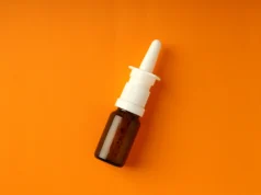 FDA aprueba primer spray nasal diurético para enfermedades del corazón, hígado y riñón Frasco marrón pequeño con aplicador en spray nasal blanco, colocado sobre un fondo naranja.