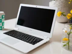 Adiós a Windows, alternativas gratuitas y sencillas para dejar Microsoft sin perder tu PC Portátil blanco Acer sobre una mesa con la pantalla apagada, acompañado de un vaso de café reutilizable y un florero con flores amarillas.