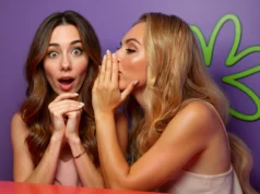 Apple elimina la app de seguridad para citas de mujeres Tea tras múltiples brechas de datos Dos mujeres en primer plano sobre un fondo morado: una susurra al oído de la otra, que reacciona sorprendida con expresión de asombro.