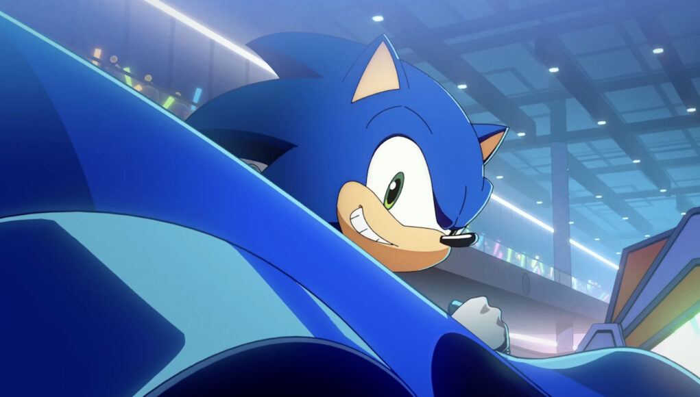 Ilustración animada de Sonic, el erizo azul, sonriendo con expresión confiada mientras conduce un vehículo de color azul en un entorno futurista iluminado con luces de neón y público al fondo.