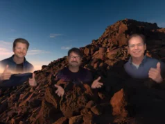 Apple crea clones digitales casi humanos, pero permanecen atrapados en un dispositivo de lujo Tres avatares semitransparentes de hombres aparecen sobre un paisaje rocoso al atardecer; los tres están sonriendo, dos de ellos levantan los pulgares y el del centro gesticula con las manos.