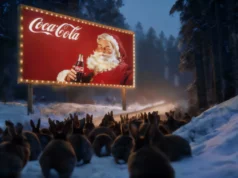 Coca-Cola presenta su nuevo anuncio navideño generado por IA con resultados visuales pobres Un grupo numeroso de conejos en un bosque nevado observa una gran valla publicitaria iluminada que muestra a Papá Noel sosteniendo una botella de Coca-Cola. La escena ocurre al atardecer o de noche, con nieve cubriendo el suelo y árboles alrededor, y una luz cálida proveniente del cartel que contrasta con el entorno frío.