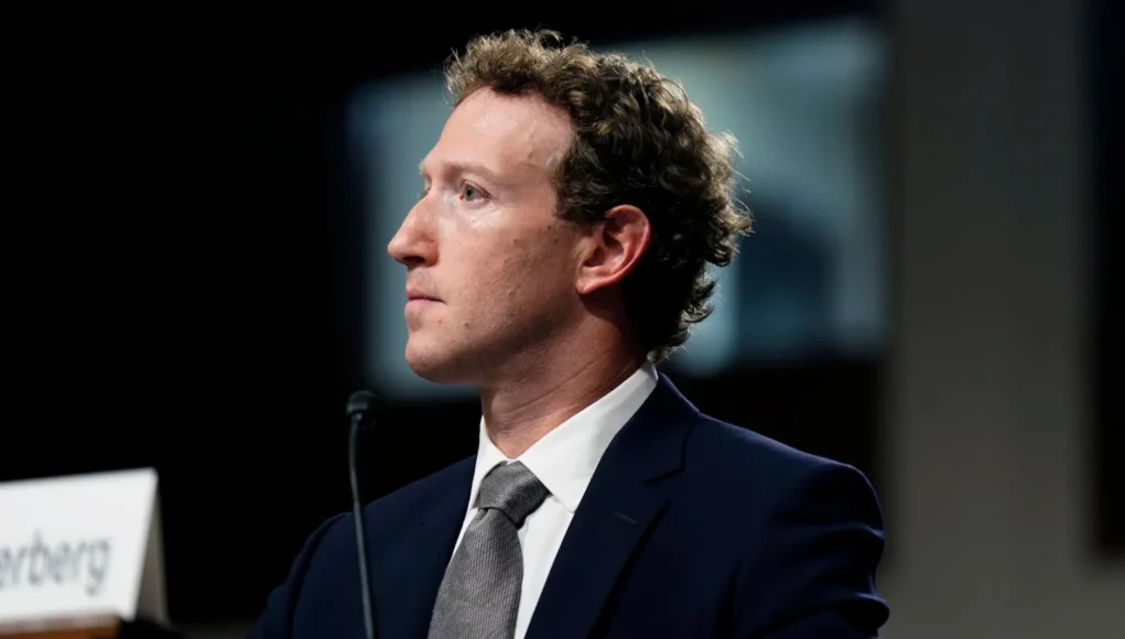 Meta Menores Un hombre joven con traje oscuro y corbata gris está sentado en una sala de audiencias, visto de perfil mientras mira hacia la izquierda. Habla frente a un micrófono sobre una mesa de madera, con un fondo desenfocado que sugiere un entorno institucional.