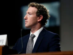 Demanda judicial revela que Meta ocultó riesgos para menores y engañó al público Un hombre joven con traje oscuro y corbata gris está sentado en una sala de audiencias, visto de perfil mientras mira hacia la izquierda. Habla frente a un micrófono sobre una mesa de madera, con un fondo desenfocado que sugiere un entorno institucional.