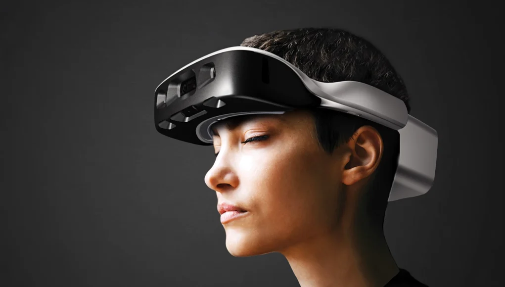 Persona con un visor de realidad mixta de diseño futurista, visto de perfil, sobre fondo oscuro, representando el uso de tecnologías avanzadas de computación espacial y realidad aumentada.