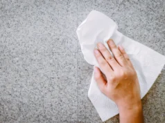 Investigadores de Stanford desarrollan ‘escudo auditivo’ para mejorar la atención en personas con TDAH Mano limpiando una superficie de piedra o encimera gris con una servilleta de papel blanca, representando una acción de limpieza doméstica.